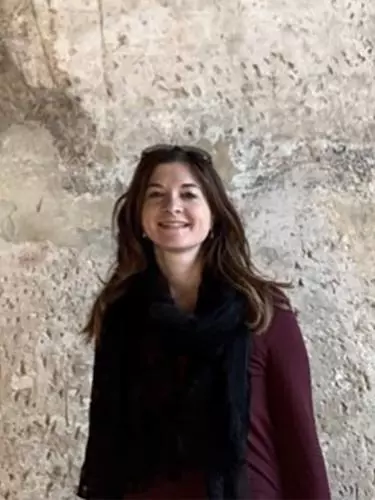 Photo of Emanuela Vai smiling to camera with rocky surface behind