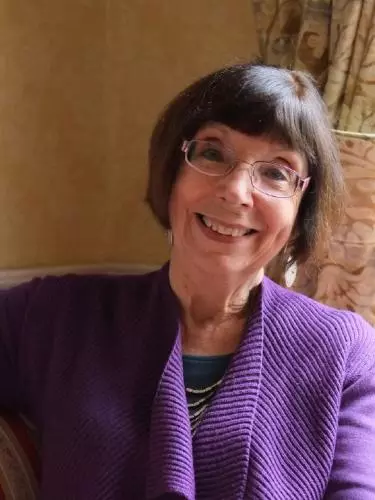 Photo of Susan Doran smiling to camera, sitting on a sofa.