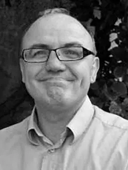 Black and white photo of Perry Gauci smiling to camera