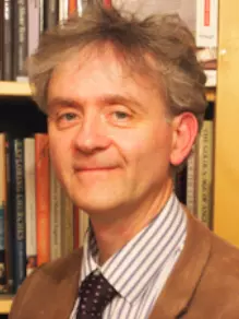 Photo of Richard Lawes looking to camera with a bookcase behind him.