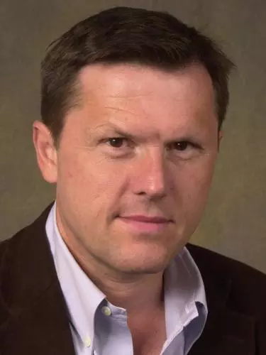 Photo of Robert Iliffe looking to camera in front of a neutral background.