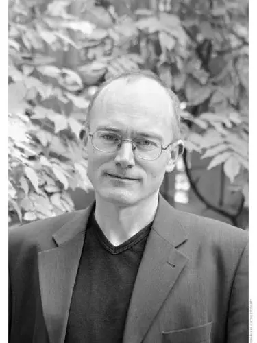 Black and white photo of Peter Wilson standing outside in front of foliage.