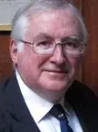 Photo of Ian Maclean looking to camera in front of a wooden panel.