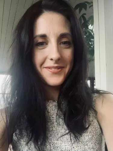 Photo of Emma Greensmith smiling to camera. A window can be seen in the background.