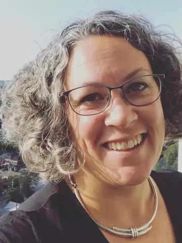 Photo of Hanna Sinclair smiling to camera. She is outside with buildings and the sky visible behind her.
