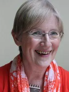 Photo of Helen Watanabe O'Kelly smiling to camera in front of a neutral background.