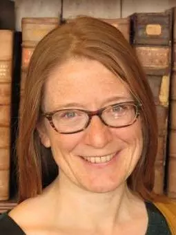 Photo of Kathryn Murphy smiling to camera, standing in front of a book shelf.