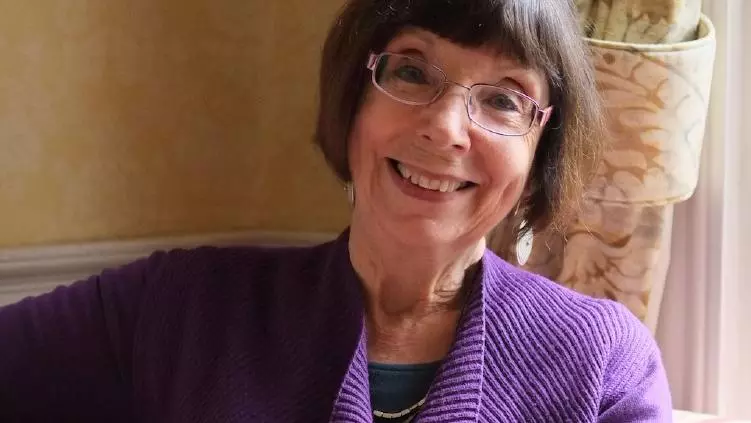 Photo of Susan Doran smiling to camera, sitting on a sofa.
