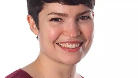 Photo of Jennifer Oliver smiling to camera, sitting in front of a white background. 