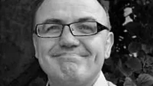 Black and white photo of Perry Gauci smiling to camera