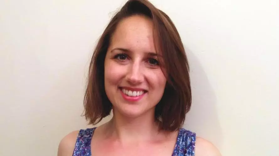 Photo of Jessica Goodman smiling to camera, standing on front of a white background. 