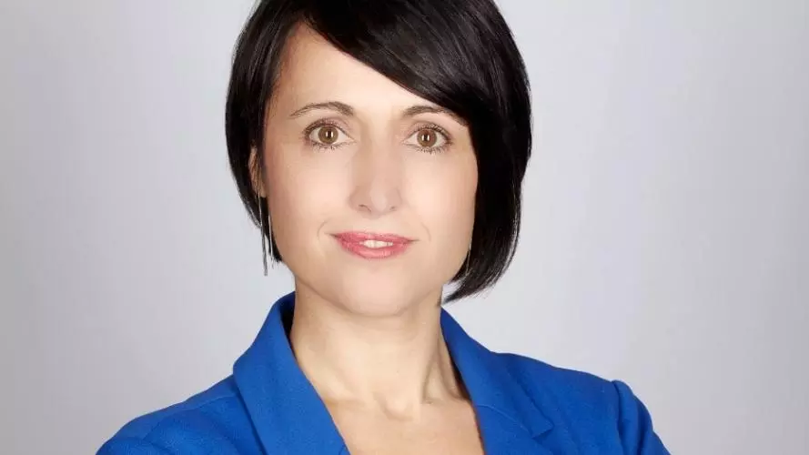 Photo of Diana Berruezo Sanchez looking to camera with her arms folded, standing in front of a white background.