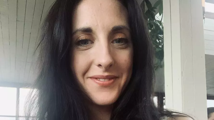 Photo of Emma Greensmith smiling to camera. A window can be seen in the background.