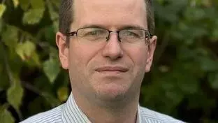 Professor Ian Williams standing against a verdant background