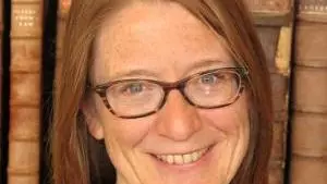 Photo of Kathryn Murphy smiling to camera, standing in front of a book shelf.