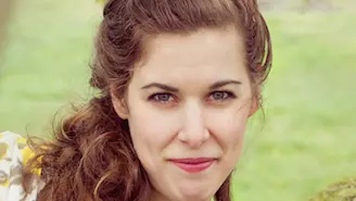 Photo of Rebecca Wallace. Smiling directly at the camera against a grassy background.